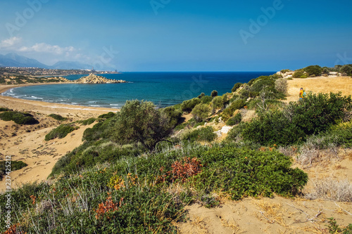 Desert coastline with sand Alagadi beach of Northern Cyprus and factory and mountains on horizon