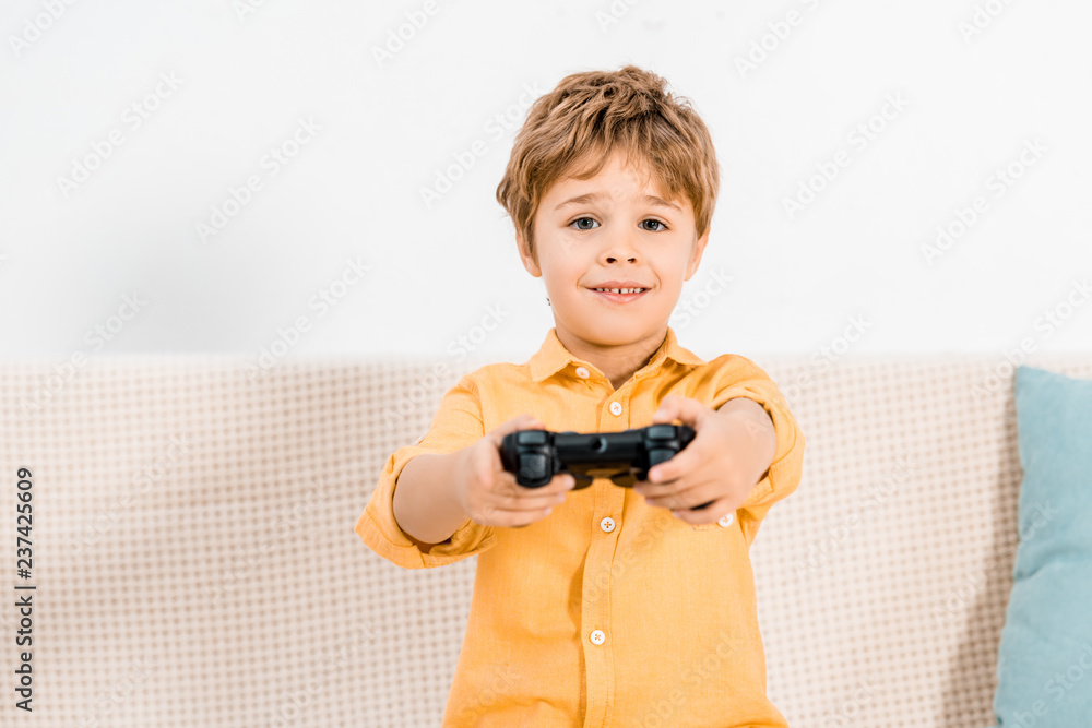 Adorable little boy playing video game with joystick and looking at camera Adorable little boy playing video game with joystick and looking at camera