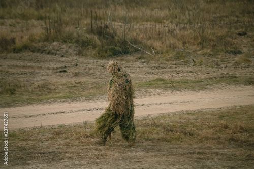 Soldier in camouflaged sniper suit searching position