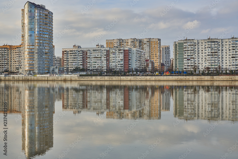 New sky in the background of the old neighborhood in the West of Krasnodar and its reflection in the river Kuban at sunset. Two worlds in one place.