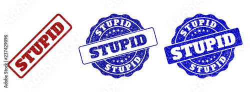 STUPID grunge stamp seals in red and blue colors. Vector STUPID labels with scratced effect. Graphic elements are rounded rectangles, rosettes, circles and text labels.