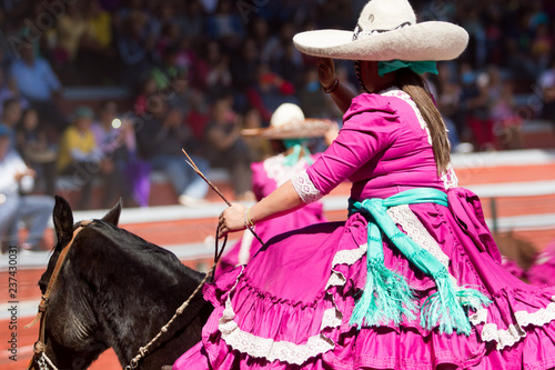 A mexican escaramuza girl salutes the audience before beginning the performance of charreada