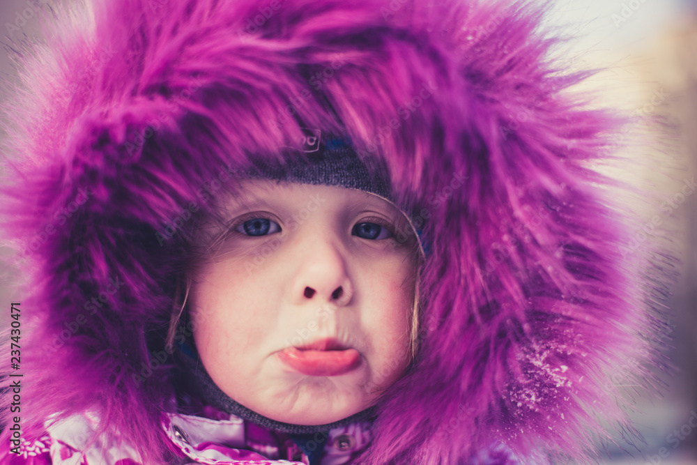 little girl in a beautiful pink jacket on a winter afternoon
