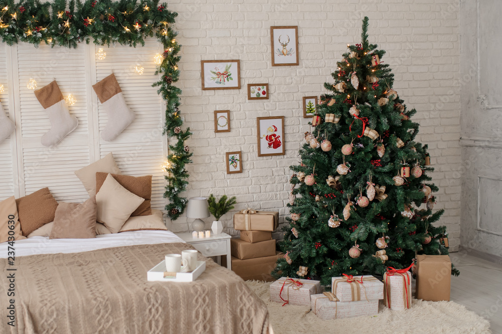 a christmas environment: a christmas tree with presents on the floors near a bed