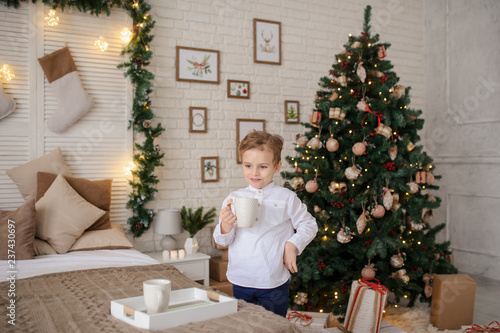 a 6-year blond boy with a cup in his hands in a christmas environment