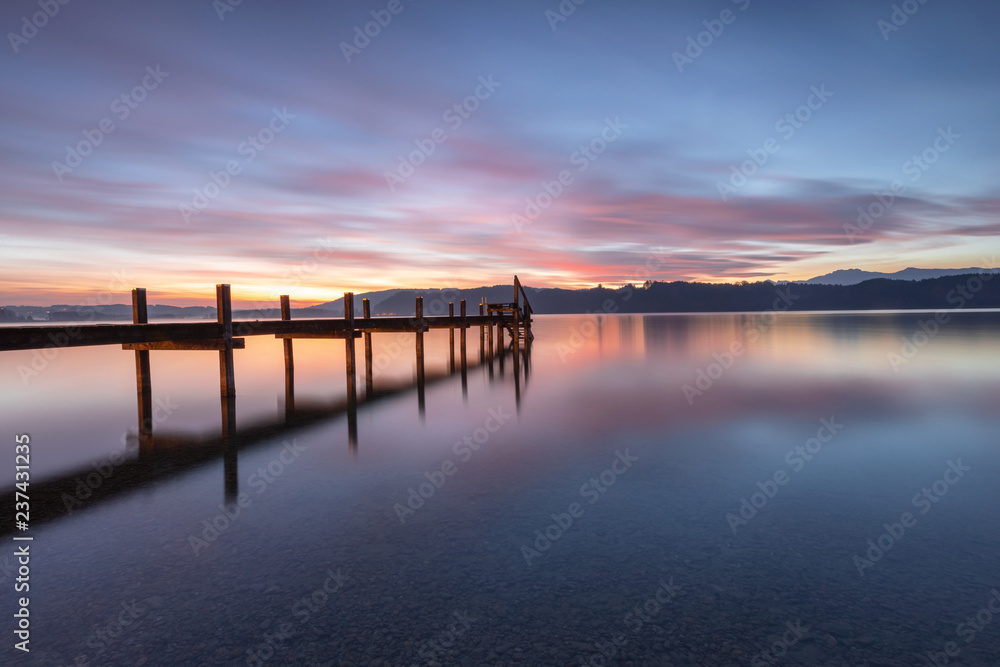 Sonnenaufgang und Steg am Simssee in Bayern, Morgenstimmung Stockfoto