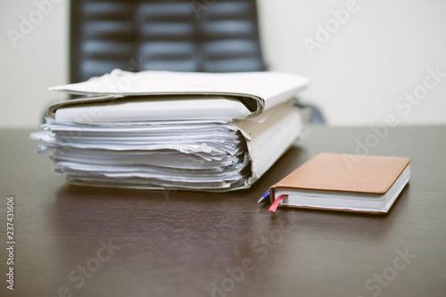 Notepad with ballpoint pen. Pile of unfinished documents on office desk, Stack of business paper. A file folders  with documents and important documents. 