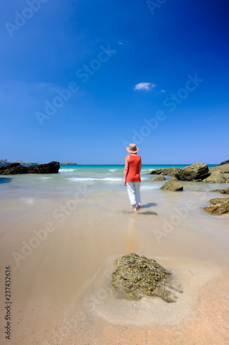 Woman standing in shallow water on a beautiful beach in Cornwall photo