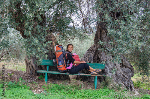 mom and baby sit on bench under two old olive trees