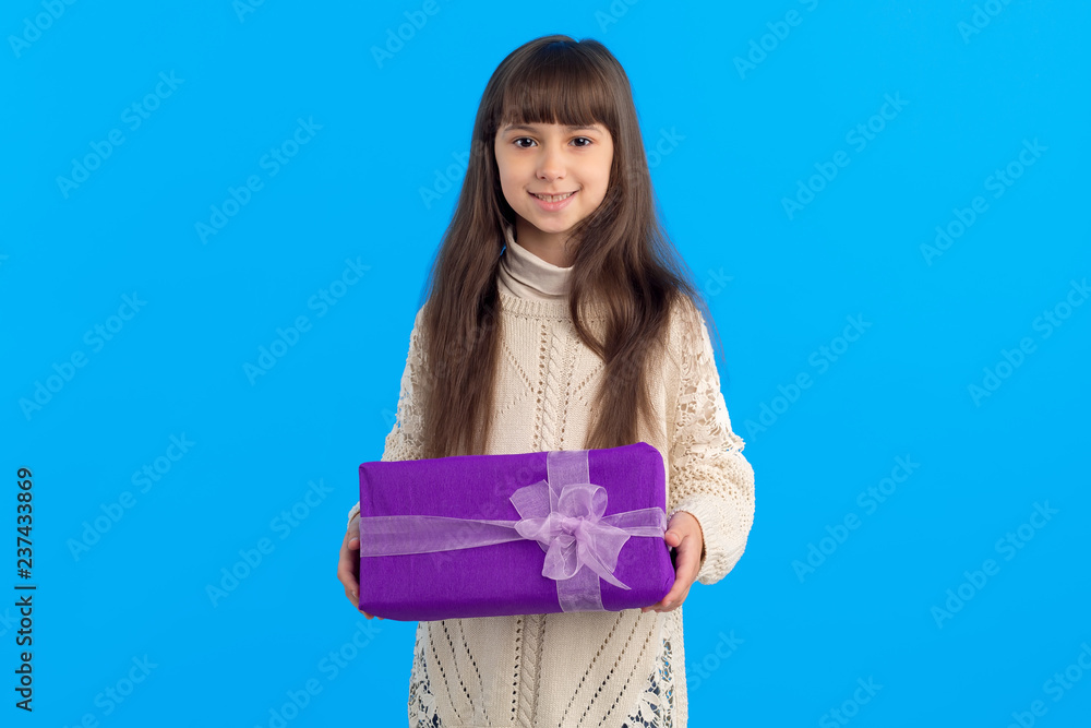 Beautiful girl with a purple box on a blue background. Gift in hands. Beautiful girl with a purple box on a blue background. Gift in hands.