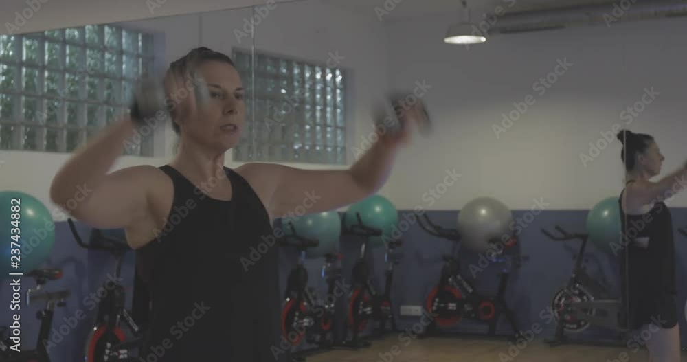 Mujer en gimnasio haciendo deporte con pesas