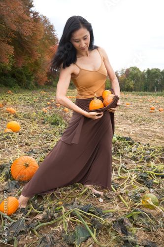 Adult woman dancing with pumpkins on a farm in Connecticut. photo