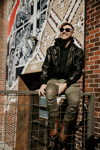 Portrait Headshots of a Young Handsome Attractive Modern Fashion Caucasian Male Guy Modeling near Local Outdoor Art in Urban City in Autumn Winter Season on Bright Sunny Day