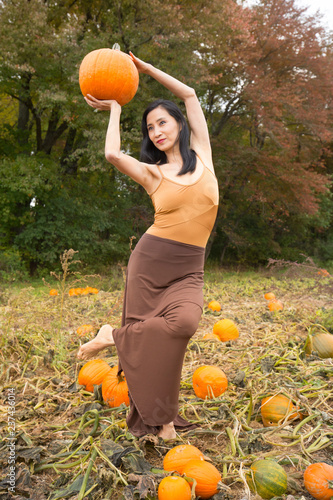 Adult woman dancing with pumpkins on a farm in Connecticut.