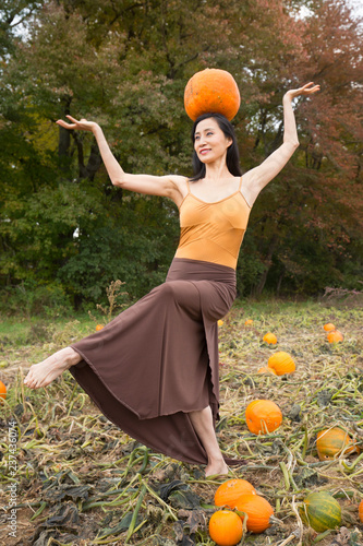 Adult woman dancing with pumpkins on a farm in Connecticut. photo