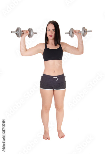 Woman standing bare feet and lifting two dumbbells