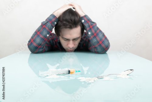 young guy looks at a syringe with heroin
