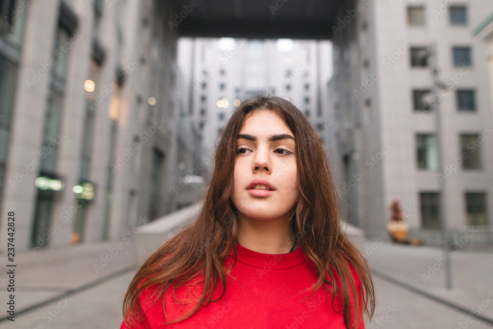 Close up portrait of an attractive girl on the background of modern urban architecture. Girl against the backdrop of a city landscape, looking away. Close up portrait of an attractive girl on the background of modern urban architecture. Girl against the backdrop of a city landscape, looking away.