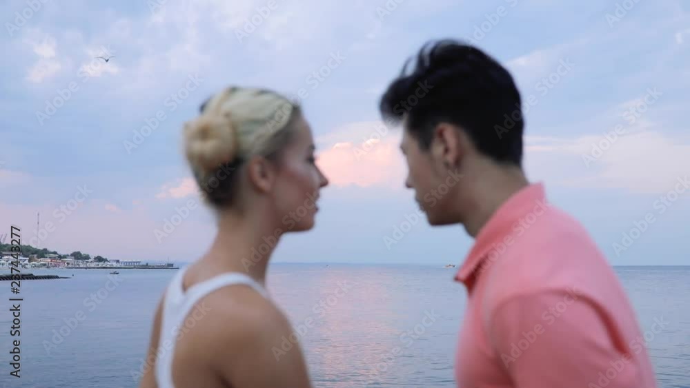 Young couple embracing each other looking at evening calm sea Young couple embracing each other looking at evening calm sea