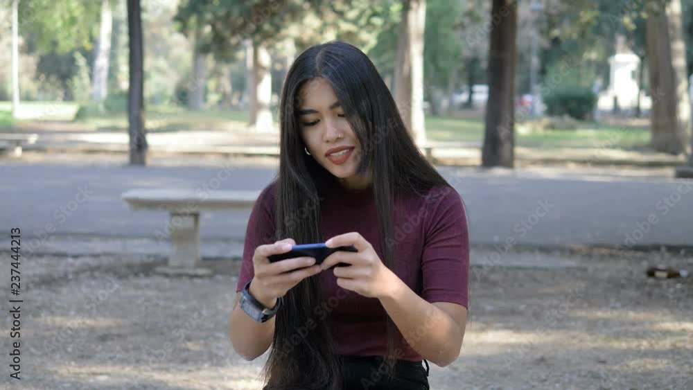 Young asian woman playing game with smartphone. Youth,game,technology-outdoor Young asian woman playing game with smartphone. Youth,game,technology-outdoor