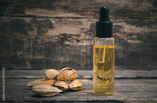 Almond nut oil in the bottle on the wooden table background.