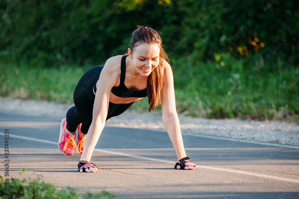 beautiful and athletic sport young woman happy smile doing push up before running in urban park training workout city in female runner body care concept beautiful and athletic sport young woman happy smile doing push up before running in urban park training workout city in female runner body care concept