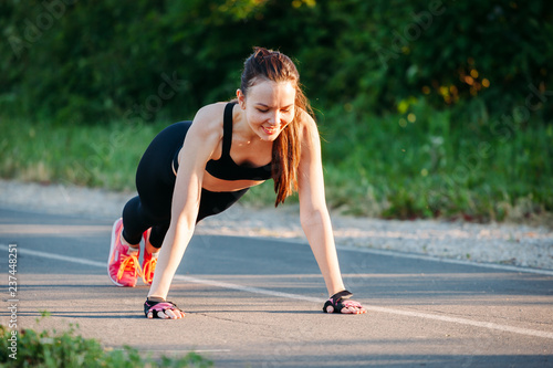  beautiful and athletic sport young woman happy smile doing push up before running in urban park training workout city in female runner body care concept