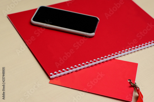 Red notebook, pen, phone and badge on a table. Business meeting