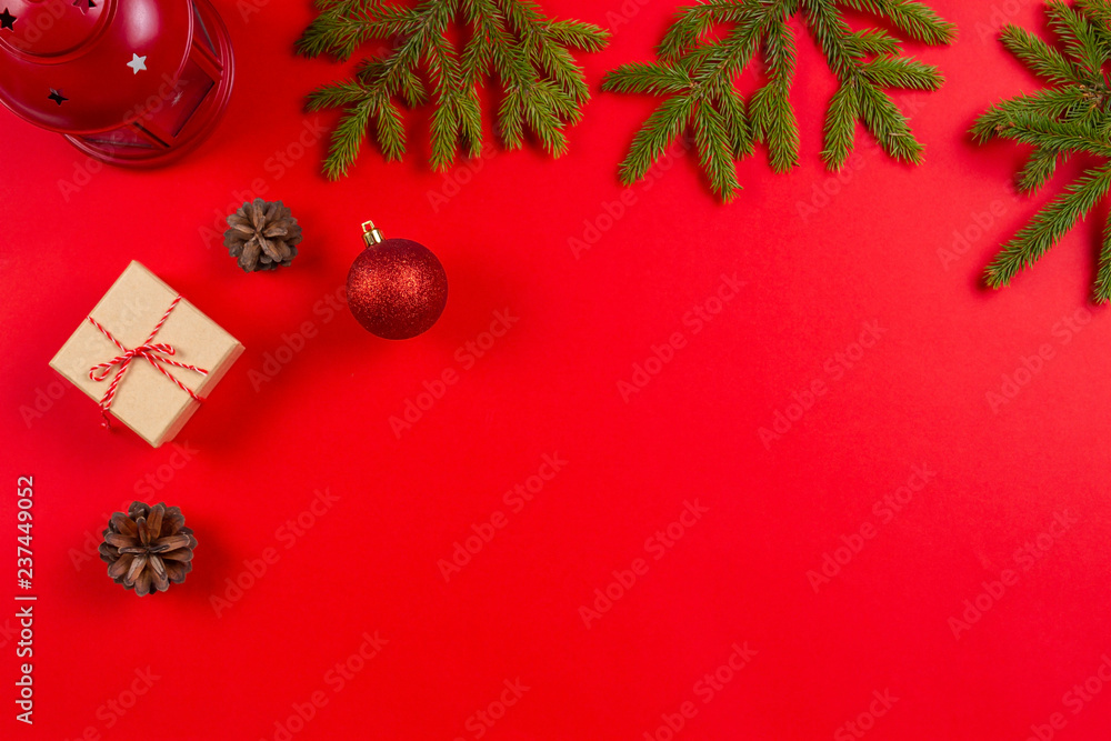 Christmas composition. Fir tree branches, pine cones Christmas decorations and present gift boxes on red background