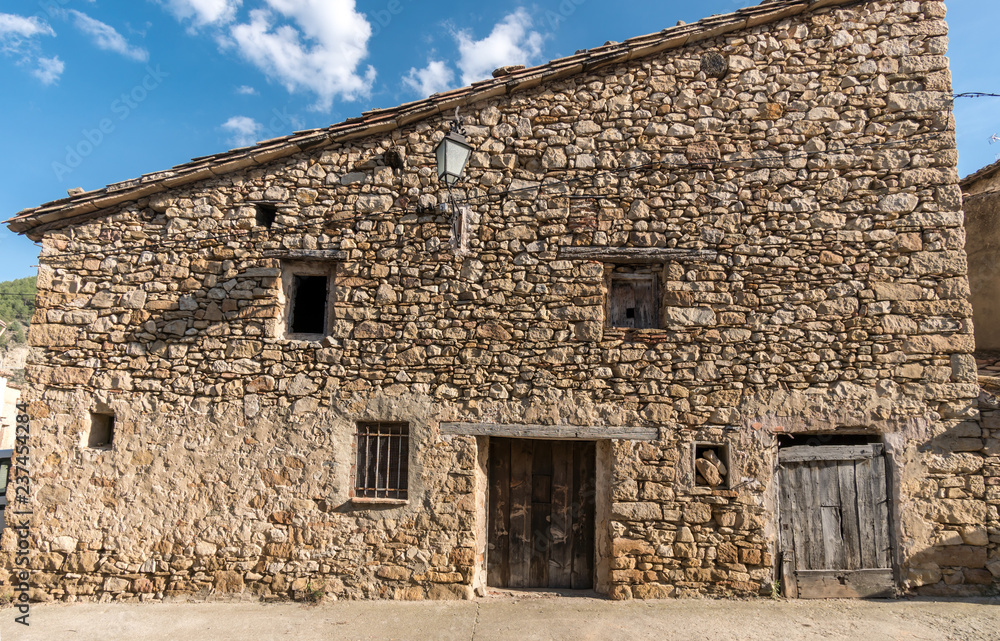 Old facade with stone cladding house, old barn in a village in spain