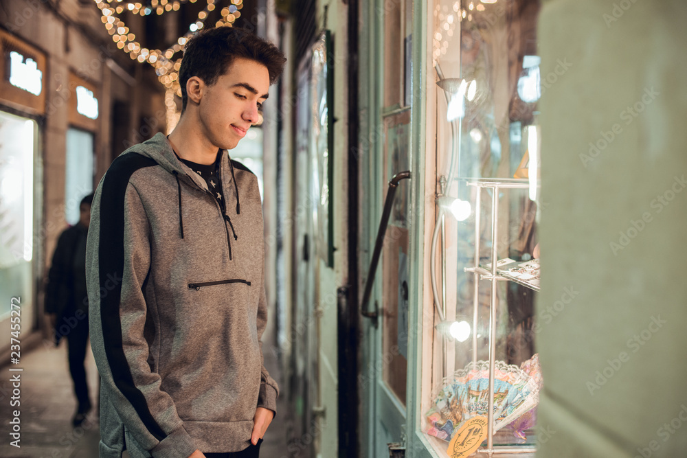 Brunette boy looking at shop at night Brunette boy looking at shop at night