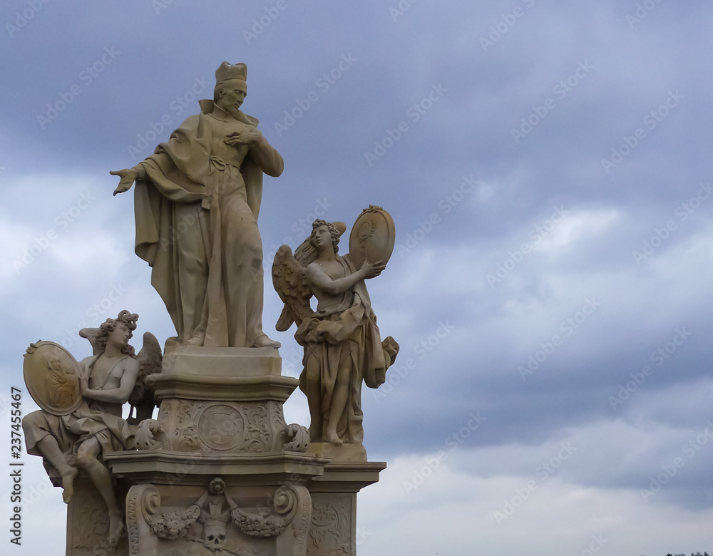 18th Century statue of St Francis Borgia & two angels. Charles Bridge, Prague. Moody clouded background.