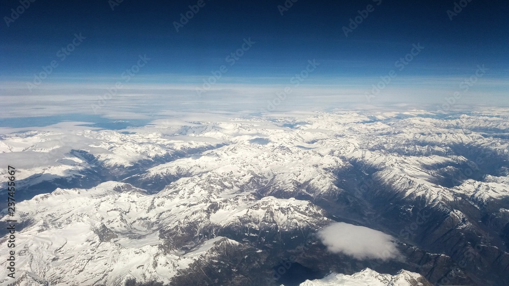 Panoramic aerial view of snow capped mountains with clear blue sky 