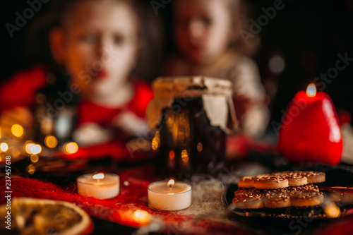 Children at the festive table. Bank of jam  candles and cookies on the table