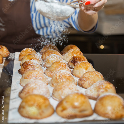 Sprinklng icing Sugar on Neapolitan Pastry: Group of Filled Pastries on a Tray © GioRez