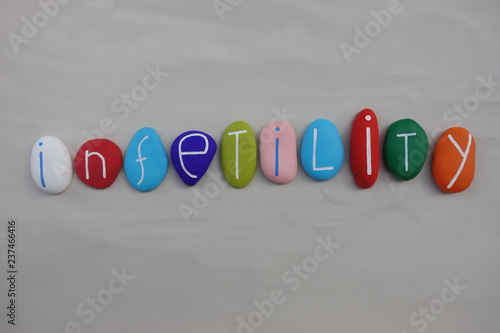 Infertility word composed with colored sea stones over white sand photo