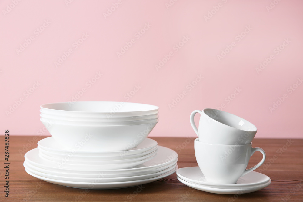 Set of clean dishes on table against color background Set of clean dishes on table against color background