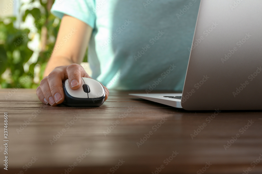 Fototapeta premium Woman using computer mouse with laptop at table, closeup