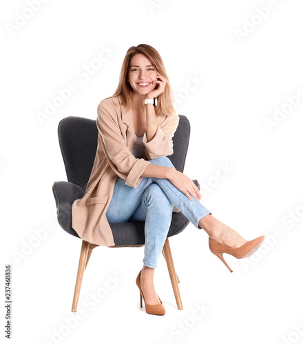 Young woman sitting in armchair on white background