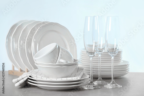 Set of clean dishes on table against light background