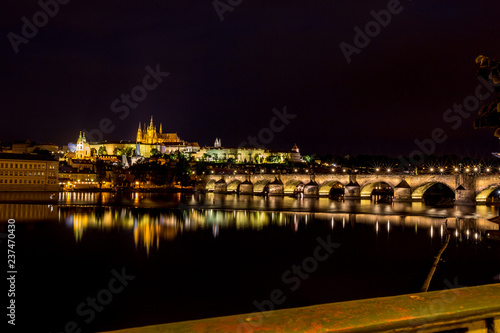 Long exposure night photo, beautiful cityscape as seen from Charles Bridge, Prague towards the old center of of the Czech Republic capital, summer nighttime with water reflections from Vltava river