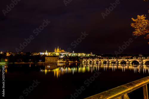 Long exposure night photo, beautiful cityscape as seen from Charles Bridge, Prague towards the old center of of the Czech Republic capital, summer nighttime with water reflections from Vltava river