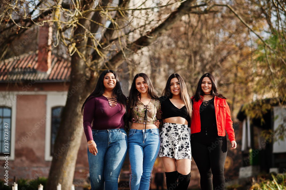 Group of four happy and pretty latino girls from Ecuador posed at street.