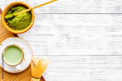 Coffee and cocktails with matcha concept. Matcha latte near bowl with matcha powder and accessories on white wooden background top view copy space photo