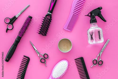 female hairdresser desk with accessories and combs on pink background top view