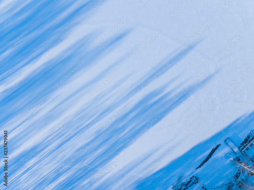 Obraz premium Aerial view on the texture of snow with shadow from trees on the surface of a winter lake 