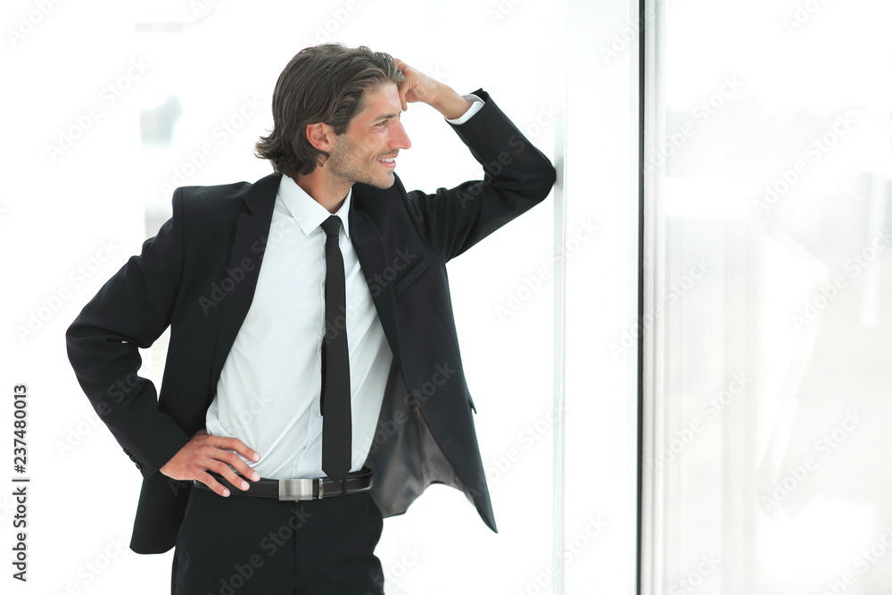 smiling businessman standing near window in office smiling businessman standing near window in office