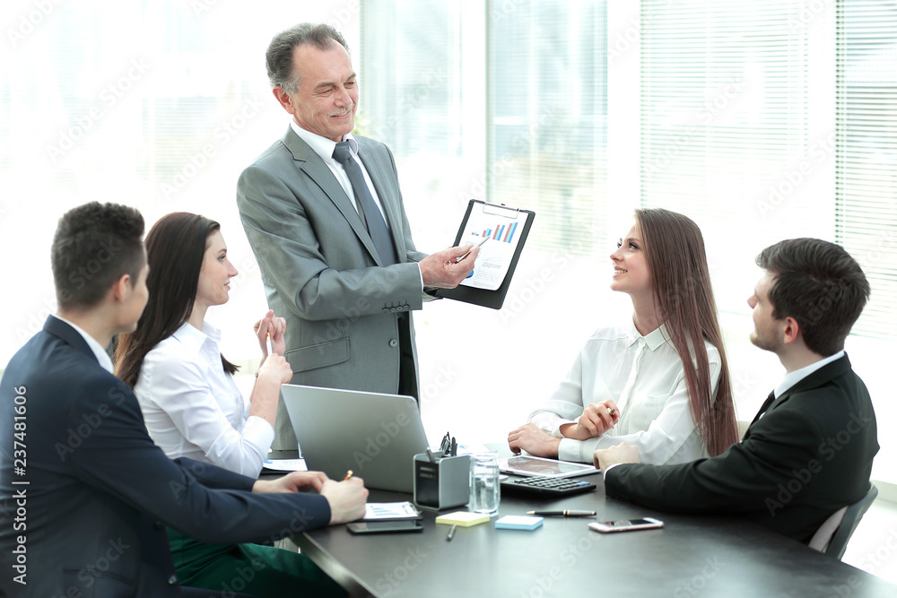 smiling Manager showing a business team ,a graph with financial data. smiling Manager showing a business team ,a graph with financial data.