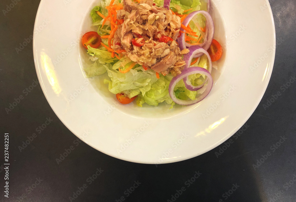 Top view Spicy tuna salad in white dish on the black wooden table. Healthy and smart eating