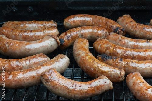 Fresh pork sausages cooking on an outdoor grill.